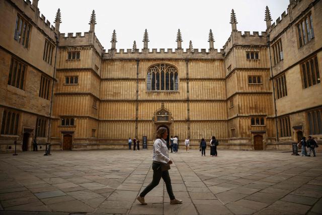 This photo taken on June 17, 2026 shows a man walking past the Bodleian Library at Oxford University in Oxford, central England. With its grand atrium, 500-seat acoustics-led concert hall and other state-of-the-art spaces, Oxford's Schwarzman Centre is the newest example of an elite UK university showcasing a billionaire's endowment. (Photo by HENRY NICHOLLS / AFP) / TO GO WITH Britain-education-universities-philanthrophy,FOCUS by Joe JACKSON