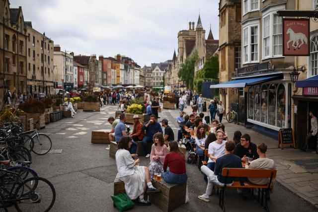 This photo taken on June 17, 2026 shows people sitting out along Broad Street, near Oxford University in Oxford, central England. With its grand atrium, 500-seat acoustics-led concert hall and other state-of-the-art spaces, Oxford's Schwarzman Centre is the newest example of an elite UK university showcasing a billionaire's endowment. (Photo by HENRY NICHOLLS / AFP) / TO GO WITH Britain-education-universities-philanthrophy,FOCUS by Joe JACKSON