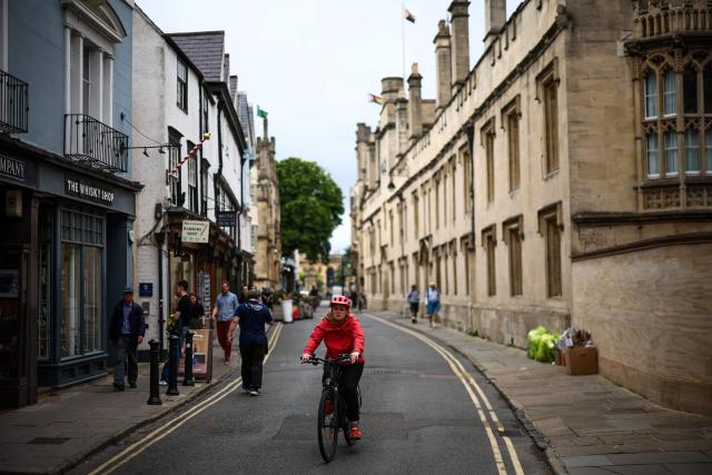 This photo taken on June 17, 2026 shows a cyclist riding down a street near Oxford University in Oxford, central England. With its grand atrium, 500-seat acoustics-led concert hall and other state-of-the-art spaces, Oxford's Schwarzman Centre is the newest example of an elite UK university showcasing a billionaire's endowment. (Photo by HENRY NICHOLLS / AFP) / TO GO WITH Britain-education-universities-philanthrophy,FOCUS by Joe JACKSON