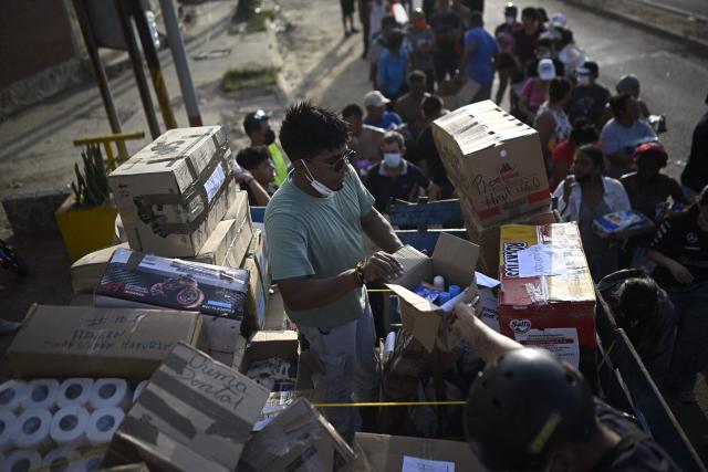 Volunteers distribute medicines and basic supplies to residents affected by twin earthquakes in the Playa Verde sector of Catia La Mar, La Guaira state, Venezuela, on June 29, 2026. Hopes were fading of finding survivors more than four days after powerful twin earthquakes struck Venezuela, as residents grow increasingly frustrated with the government's response to the disaster that has killed -up to now- more than 1,700 people and left tens of thousands unaccounted for. (Photo by Federico PARRA / POOL / AFP)