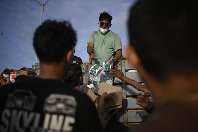A volunteer distributes medicines and basic supplies to residents affected by twin earthquakes in the Playa Verde sector of Catia La Mar, La Guaira state, Venezuela, on June 29, 2026. Hopes were fading of finding survivors more than four days after powerful twin earthquakes struck Venezuela, as residents grow increasingly frustrated with the government's response to the disaster that has killed -up to now- more than 1,700 people and left tens of thousands unaccounted for. (Photo by Federico PARRA / POOL / AFP)
