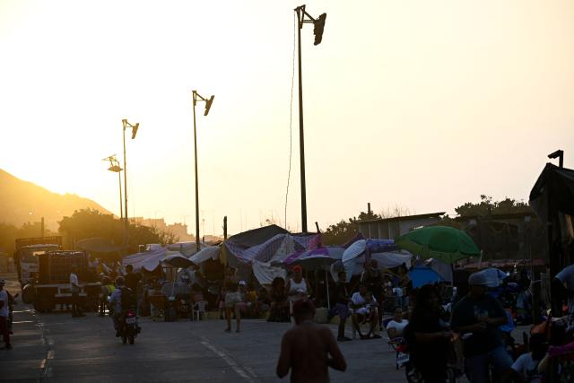 Displaced residents gather under makeshift tarpaulin shelters along a roadside in the Playa Verde sector of Catia La Mar, La Guaira state, Venezuela, on June 29, 2026, following twin earthquakes. Hopes were fading of finding survivors more than four days after powerful twin earthquakes struck Venezuela, as residents grow increasingly frustrated with the government's response to the disaster that has killed -up to now- more than 1,700 people and left tens of thousands unaccounted for. (Photo by Federico PARRA / POOL / AFP)