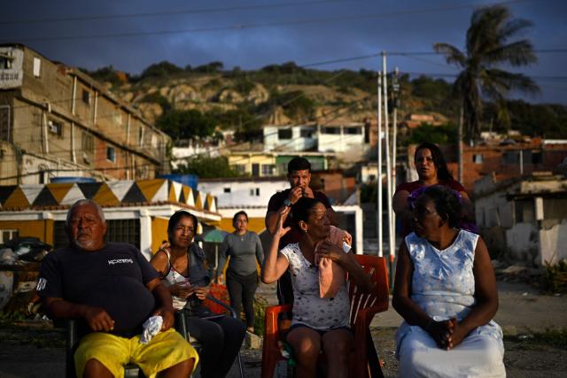 Residents gather outdoors near damaged buildings in the Playa Verde sector of Catia La Mar, La Guaira state, Venezuela, on June 29, 2026, following twin earthquakes. Hopes were fading of finding survivors more than four days after powerful twin earthquakes struck Venezuela, as residents grow increasingly frustrated with the government's response to the disaster that has killed -up to now- more than 1,700 people and left tens of thousands unaccounted for. (Photo by Federico PARRA / POOL / AFP)