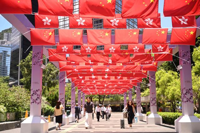 People walk under Hong Kong and Chinese flags marking the 29th anniversary of the handover of Hong Kong from Britain to China on a street in Hong Kong on June 30, 2026. (Photo by Peter PARKS / AFP)