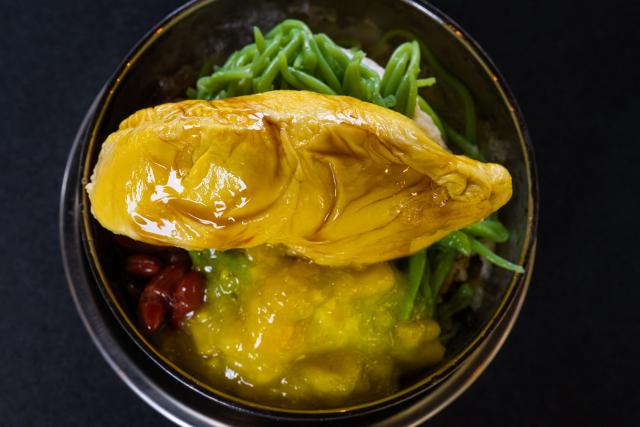 This photo taken on June 27, 2026 shows a cendol dessert topped with Musang King durian pulp for sale in Karak, in Malaysia's Pahang state. Found across Southeast Asia, the spiky fruit comes in many varieties and in Malaysia, the highly prized cultivar Musang King is consumed locally and exported, mainly to China. Malaysia, which produces more than 550,000 tonnes of durian a year, is currently in its peak harvest season. (Photo by Mohd Rasfan / AFP)