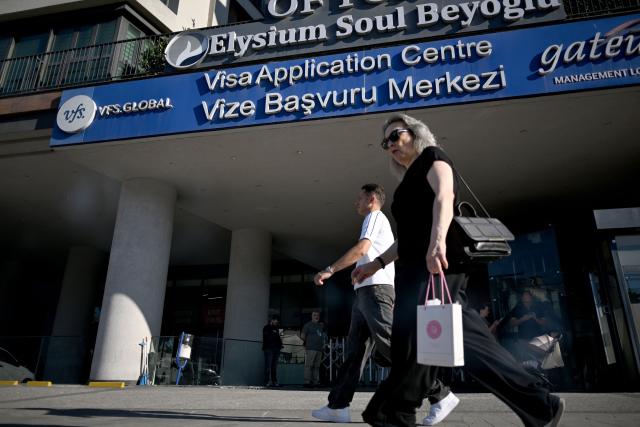 Pedestrians walk past the entrance of a visa application centre to apply for Schengen visas, in Istanbul on June 30, 2026. According to data published by the European Commission, of the 1.25 million visa applications for the Schengen Area (26 countries, mostly European Union members) submitted in Turkey in 2025, 1.07 million were approved. (Photo by Ozan KOSE / AFP)