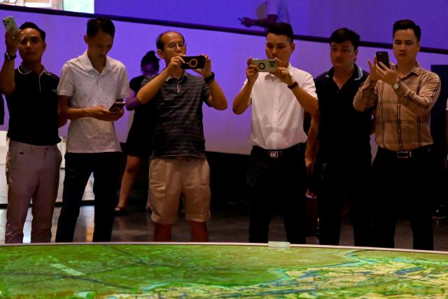 Men take photos at an exhibition for Hanoi's 100-year development master plan at the Hanoi Museum in Hanoi on June 30, 2026. (Photo by Nhac NGUYEN / AFP)