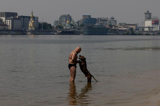 CORRECTION / TOPSHOT - A man stands with his dog in the Dnipro River on Trukhaniv Island during a hot summer’s day in Kyiv on June 29, 2026, amid the Russian invasion of Ukraine. (Photo by Tetiana DZHAFAROVA / AFP) / “The erroneous mention[s] appearing in the metadata of this photo by Tetiana DZHAFAROVA has been modified in AFP systems in the following manner: [---] instead of [---]. Please immediately remove the erroneous mention[s] from all your online services and delete it (them) from your servers. If you have been authorized by AFP to distribute it (them) to third parties, please ensure that the same actions are carried out by them. Failure to promptly comply with these instructions will entail liability on your part for any continued or post notification usage. Therefore we thank you very much for all your attention and prompt action. We are sorry for the inconvenience this notification may cause and remain at your disposal for any further information you may require.”