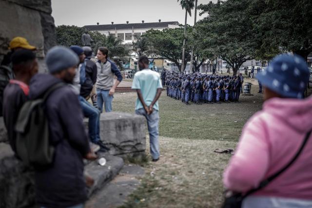 Residents watch as members of the South African Police Service (SAPS) stand in formation to receive instructions ahead of planned demonstrations by the March and March movement against the presence of undocumented migrants in South Africa in Durban, on June 30, 2026. South African police deployed to head off unrest and protests on June 30, 2026, the unofficial deadline set by citizen-led groups for undocumented foreign nationals to leave that has already pushed thousands to flee.
Officers were out in force to prevent violence and looting, while hundreds of foreign nationals took refuge in several cities, urgently seeking help to leave. (Photo by Marco LONGARI / AFP)