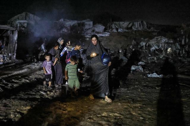 Palestinians make their way amid destroyed shelters at the site of an Israeli strike that was reportedly preceded by an Israeli military evacuation warning, at the al-Mawassi camp in Khan Yunis, southern Gaza Strip, late on June 29, 2026. Gaza remains gripped by daily violence, with both the Israeli military and Hamas accusing one another of violating the truce in effect since October 10. (Photo by Bashar Taleb / AFP)