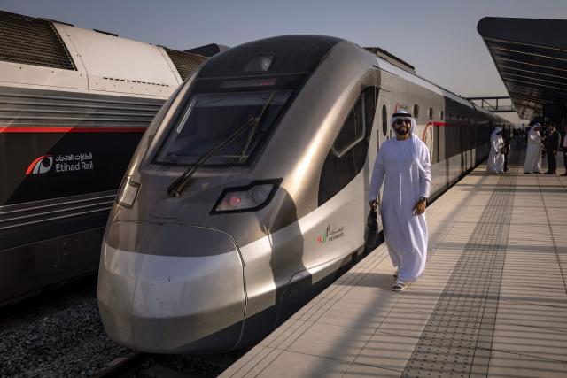 A man stands next to an Etihad Rail train, the UAE's first passenger train, on its inaugural journey at Mohamed bin Zayed City station in Abu Dhabi on June 30, 2026. The passenger service will eventually connect four of the country's seven emirates, with an "introductory operational phase" between Abu Dhabi and Fujairah to begin on June 30, state news agency WAM said earlier this month. The Dubai station will open on September 30, while the main station in the neighbouring emirate of Sharjah is set to be operational on March 30, 2027. (Photo by FADEL SENNA / AFP)