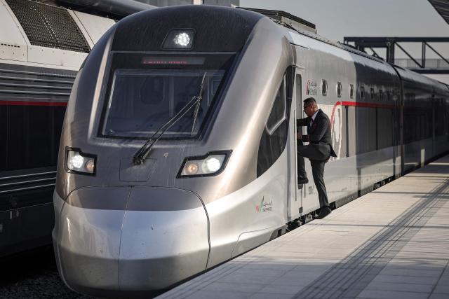 An Etihad Rail employee boards the locomotive of the UAE's first passenger train on its inaugural journey at Mohamed bin Zayed City station in Abu Dhabi on June 30, 2026. The passenger service will eventually connect four of the country's seven emirates, with an "introductory operational phase" between Abu Dhabi and Fujairah to begin on June 30, state news agency WAM said earlier this month. The Dubai station will open on September 30, while the main station in the neighbouring emirate of Sharjah is set to be operational on March 30, 2027. (Photo by FADEL SENNA / AFP)