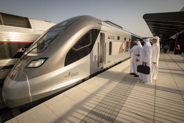 Men look at the locomotive of an Etihad Rail train, the UAE's first passenger train, on its inaugural journey at Mohamed bin Zayed City station in Abu Dhabi on June 30, 2026. The passenger service will eventually connect four of the country's seven emirates, with an "introductory operational phase" between Abu Dhabi and Fujairah to begin on June 30, state news agency WAM said earlier this month. The Dubai station will open on September 30, while the main station in the neighbouring emirate of Sharjah is set to be operational on March 30, 2027. (Photo by FADEL SENNA / AFP)