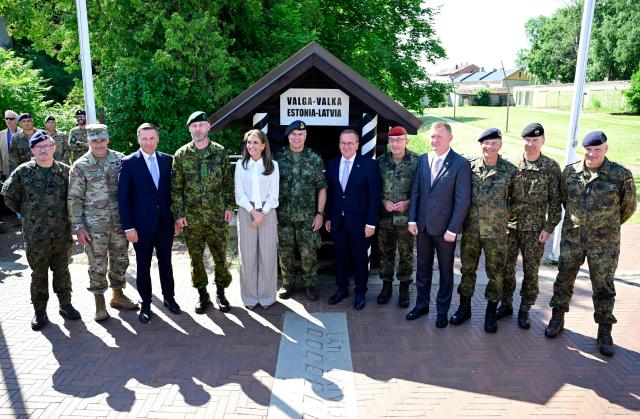 Estonian Defence Minister Hanno Pevkur (3rd L), Dutch Defence Minister Dilan Yesilgoz-Zegerius (5th L), German Defence Minister Boris Pistorius (6th R) and Latvia's Defence Minister Raivis Melnis (4th R) along with commanding officers stand on the border crossing between Estonia (L) and Latvia (R) as they attend a NATO Change of Command ceremony on June 30, 2026 in Valka (Latvia) or Valga (Estonia). A joint German-Dutch army corps (1GNC) is taking command of NATO land forces in Latvia and Estonia. Officially transitioning on June 30, 2026, this move establishes a dedicated second corps headquarters on the eastern flank to speed up reinforcements and command combat operations in the Baltic region. (Photo by John MACDOUGALL / AFP)