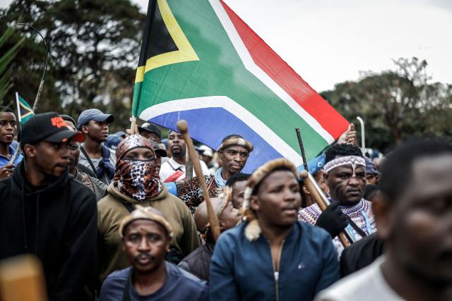 Members of the Zulu regiment known as the ‘Amabutho’ hold a South African flag as they march during a demonstration by the "March and March" movement marking an unofficial deadline set by citizen-led groups for undocumented foreign nationals to leave South Africa, in Durban, on June 30, 2026. South African police deployed to head off unrest and protests on June 30, 2026, the unofficial deadline set by anti-immigrant groups for undocumented foreign nationals to leave that has already pushed thousands to flee.
Officers were out in force to prevent violence and looting by the xenophobic groups, while hundreds of foreign nationals took refuge in several cities, urgently seeking help to leave. (Photo by Marco LONGARI / AFP)