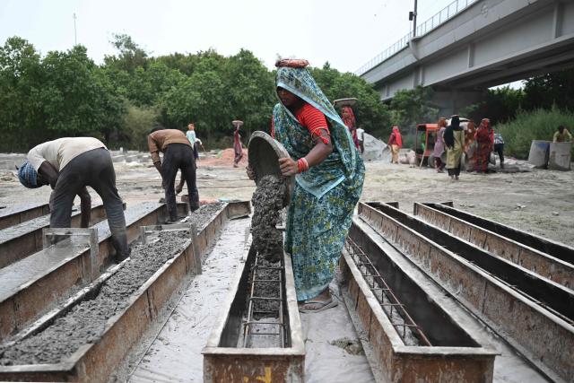 Workers make cement poles at a workshop in New Delhi on June 30, 2026. (Photo by Arun SANKAR / AFP)