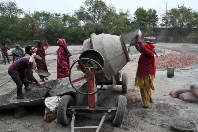 Workers make cement poles at a workshop in New Delhi on June 30, 2026. (Photo by Arun SANKAR / AFP)