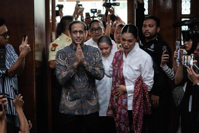 Nadiem Makarim (L), Indonesia's former education minister and co-founder of ride hailing company Gojek, gestures to the media with his wife Franka Franklin (R) as they arrive for a verdict hearing at the Central Jakarta District Court in Jakarta on June 30, 2026, in a corruption case related to the procurement of Chromebook laptops for schools during the Covid-19 pandemic. Judges found him guilty of corruption, sentencing him to 10 years in prison. The court also ordered Nadiem to pay a fine of 1 billion rupiah ($55,850) and 809 billion rupiah (more than $45 million) in restitution, or serve an additional prison term. (Photo by YASUYOSHI CHIBA / AFP)