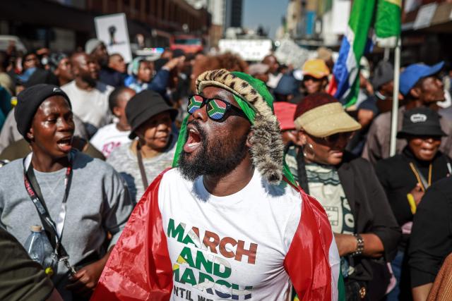 TOPSHOT - Protesters chant slogans as they march during a demonstration by the "March and March" and Operation Dudula movements marking an unofficial deadline set by citizen-led groups for undocumented foreign nationals to leave South Africa, in downtown Pretoria, on June 30, 2026. South African police deployed to head off unrest and protests on June 30, 2026, the unofficial deadline set by anti-immigrant groups for undocumented foreign nationals to leave that has already pushed thousands to flee.
Officers were out in force to prevent violence and looting by the xenophobic groups, while hundreds of foreign nationals took refuge in several cities, urgently seeking help to leave. (Photo by PHILL MAGAKOE / AFP)