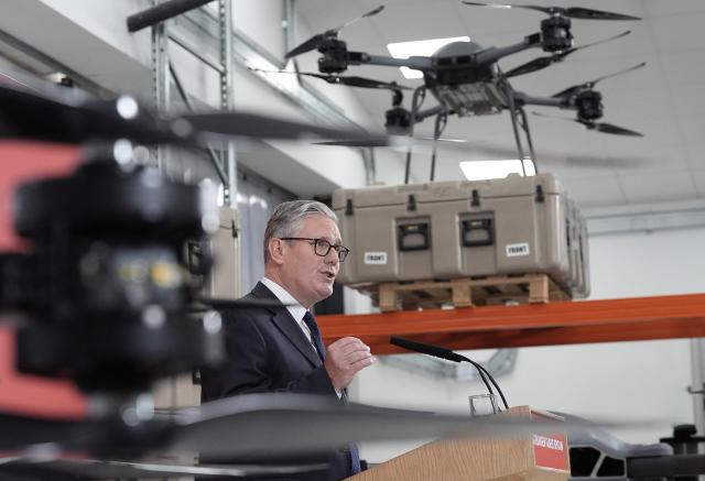 Britain's Prime Minister Keir Starmer stands beneath display of UAV drones, as he delivers a speech in Berkshire west of London, on June 30, 2026, following the publication of long-delayed Defence Investment Plan (DIP). Outgoing Prime Minister Keir Starmer announced on June 30, his long-delayed plan for funding Britain's future defence needs, with increased money for drones and autonomous systems. (Photo by Stefan Rousseau / POOL / AFP)
