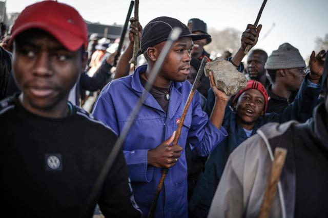 A protester holds a stone and a stick while marching with others during a demonstration by the "March and March" and Operation Dudula movements marking an unofficial deadline set by citizen-led groups for undocumented foreign nationals to leave South Africa, in Johannesburg, on June 30, 2026. South African police deployed to head off unrest and protests on June 30, 2026, the unofficial deadline set by anti-immigrant groups for undocumented foreign nationals to leave that has already pushed thousands to flee.
Officers were out in force to prevent violence and looting by the xenophobic groups, while hundreds of foreign nationals took refuge in several cities, urgently seeking help to leave. (Photo by EMMANUEL CROSET / AFP)