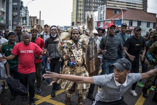 Members of the Zulu regiment known as the ‘Amabutho’ chant slogans as they march during a demonstration by the "March and March" movement marking an unofficial deadline set by citizen-led groups for undocumented foreign nationals to leave South Africa, in Durban, on June 30, 2026. Thousands of demonstrators massed across South African cities on June 30, 2026, venting anger at undocumented foreign nationals as police mounted a major operation to head off looting and xenophobic violence that has claimed four lives. 
The nationwide protests cap weeks of demonstrations called by a loose coalition of minor political parties and small citizen-led vigilante groups, which set an unofficial June 30 deadline for foreigners without residency papers to leave. (Photo by MARCO LONGARI / AFP)