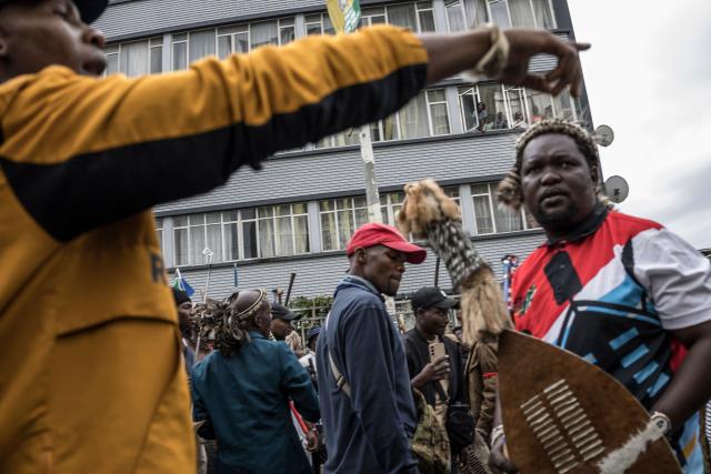 Residents observe from their apartments as members of the Zulu regiment known as the “Amabutho” chant slogans while marching during a demonstration by the "March and March" movement marking an unofficial deadline set by citizen-led groups for undocumented foreign nationals to leave South Africa, in Durban, on June 30, 2026. Thousands of demonstrators massed across South African cities on June 30, 2026, venting anger at undocumented foreign nationals as police mounted a major operation to head off looting and xenophobic violence that has claimed four lives. 
The nationwide protests cap weeks of demonstrations called by a loose coalition of minor political parties and small citizen-led vigilante groups, which set an unofficial June 30 deadline for foreigners without residency papers to leave. (Photo by MARCO LONGARI / AFP)