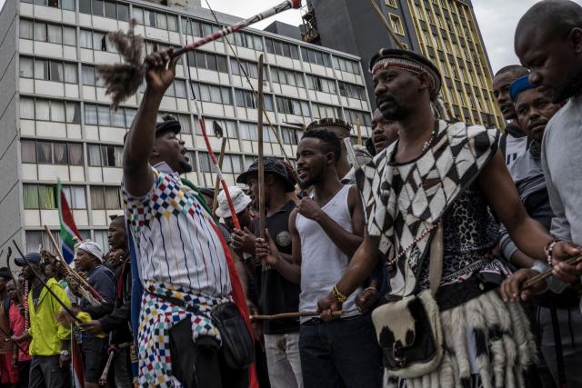 TOPSHOT - Residents observe from their apartments as members of the Zulu regiment known as the “Amabutho” chant slogans while marching during a demonstration by the "March and March" movement marking an unofficial deadline set by citizen-led groups for undocumented foreign nationals to leave South Africa, in Durban, on June 30, 2026. Thousands of demonstrators massed across South African cities on June 30, 2026, venting anger at undocumented foreign nationals as police mounted a major operation to head off looting and xenophobic violence that has claimed four lives. 
The nationwide protests cap weeks of demonstrations called by a loose coalition of minor political parties and small citizen-led vigilante groups, which set an unofficial June 30 deadline for foreigners without residency papers to leave. (Photo by MARCO LONGARI / AFP)