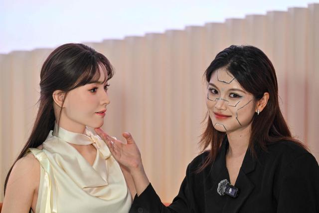 A woman (R) interacts with a humanoid robot (L) during the launch of the U1 humanoid robot produced by UWORLD, a brand under UBTECH Robotics, in Shenzhen, China's Guangdong province on June 30, 2026. Silicone skin, soothing voice: Chinese company UBTech unveiled unprecedented hyper-realistic human-looking androids equipped with artificial intelligence (AI) and presented as anti-loneliness remedies. (Photo by ADEK BERRY / AFP)