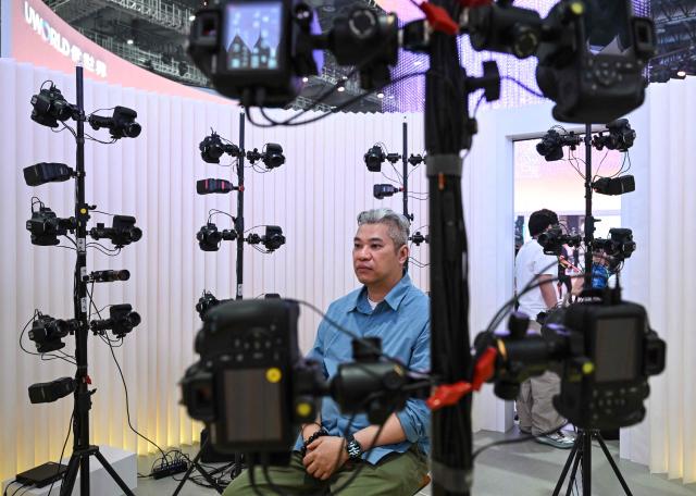 A man has his face scanned as part of a demonstration to create a customised humanoid robot during the launch of the U1 humanoid robot produced by UWORLD, a brand under UBTECH Robotics, in Shenzhen, China's Guangdong province on June 30, 2026. Silicone skin, soothing voice: Chinese company UBTech unveiled unprecedented hyper-realistic human-looking androids equipped with artificial intelligence (AI) and presented as anti-loneliness remedies. (Photo by ADEK BERRY / AFP)