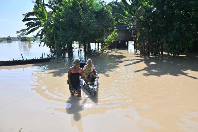 A woman pushes a boat carrying her grandmother through floodwaters in Dhemaji on June 30, 2026. (Photo by Biju BORO / AFP)
