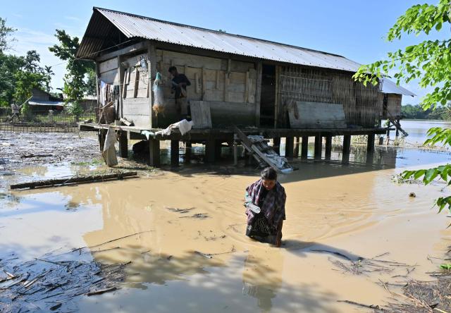 A girl wades through floodwaters in Dhemaji on June 30, 2026. (Photo by Biju BORO / AFP)