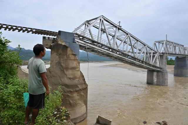 A villager looks at a damaged railway bridge following monsoon floods in Dhemaji on June 30, 2026. (Photo by Biju BORO / AFP)