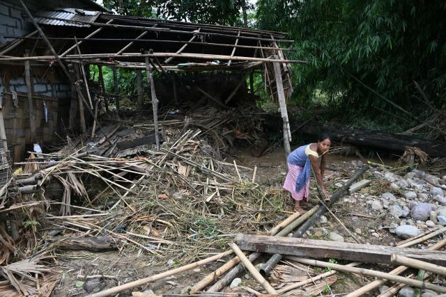 A villager collects bamboo after floodwaters damaged her house in Dhemaji on June 30, 2026. (Photo by Biju BORO / AFP)