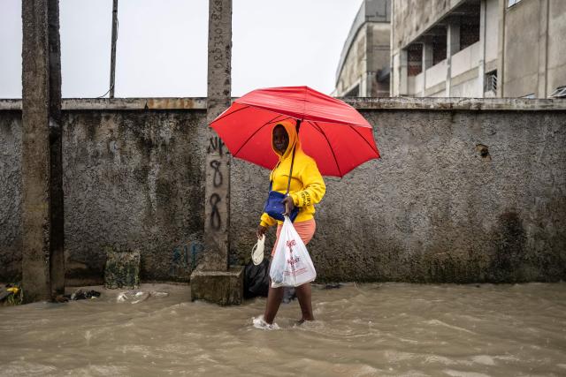 TOPSHOT - A pedestrian carrying an umbrella looks on a as she wades through a flooded street during rainfall in Lagos, on June 30, 2026. (Photo by OLYMPIA DE MAISMONT / AFP)