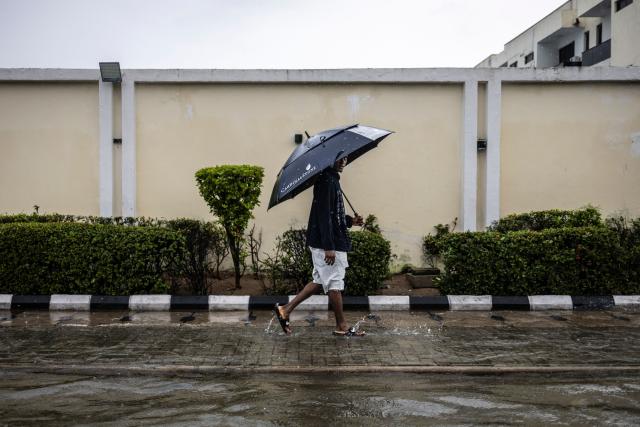 A pedestrian looks on as he walks on the side of a flooded street during rainfall in Lagos, on June 30, 2026. (Photo by OLYMPIA DE MAISMONT / AFP)