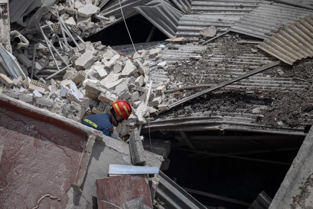 A Greek firefighter searches for victims amid the rubble at the site of a building collapse in the Petralona neighbourhood of Athens, on June 30, 2026. Construction work was underway on a neighboring plot of land and may have been the cause of the collapse, which occurred gradually, of a residential apartment building in Athens on June 30, 2026. (Photo by Angelos TZORTZINIS / AFP)