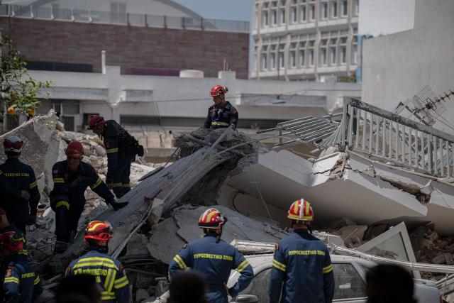 Emergency personnel search for victims amid the rubble at the site of a building collapse in the Petralona neighbourhood of Athens, on June 30, 2026. Construction work was underway on a neighboring plot of land and may have been the cause of the collapse, which occurred gradually, of a residential apartment building in Athens on June 30, 2026. (Photo by Angelos TZORTZINIS / AFP)