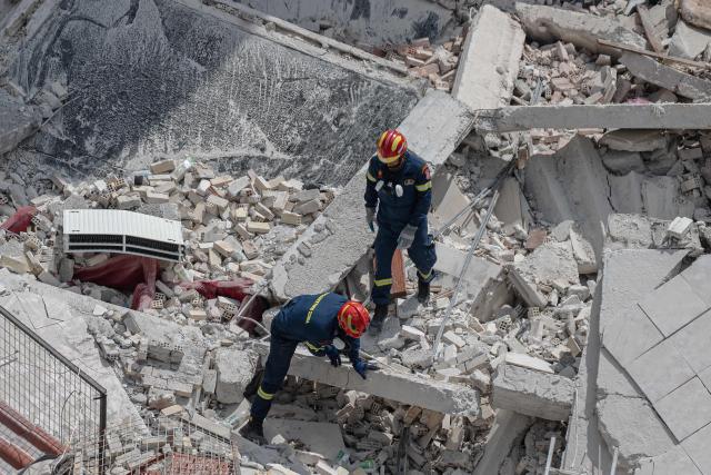 Emergency personnel search for victims amid the rubble at the site of a building collapse in the Petralona neighbourhood of Athens, on June 30, 2026. Construction work was underway on a neighboring plot of land and may have been the cause of the collapse, which occurred gradually, of a residential apartment building in Athens on June 30, 2026. (Photo by Angelos TZORTZINIS / AFP)