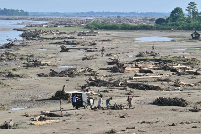 Villagers collect firewood from Simen riverbed after floodwaters receded in Dhemaji on June 30, 2026. (Photo by Biju BORO / AFP)