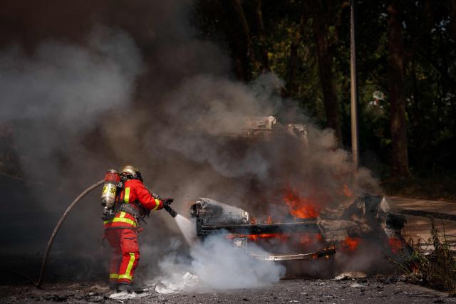 A firefighter attempts to extinguish a burning vehicle in L'ile-Saint-Denis (Saint-Denis Island), northern Paris suburb, on June 30, 2026. (Photo by Dimitar DILKOFF / AFP)