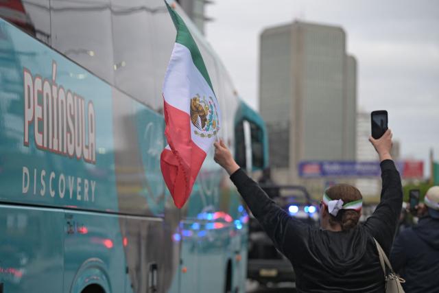 Fans cheer as the bus carrying Iran's players leaves the base camp as the team departs following its elimination from the 2026 World Cup football tournament in Tijuana on June 30, 2026. (Photo by Guillermo Arias / AFP)