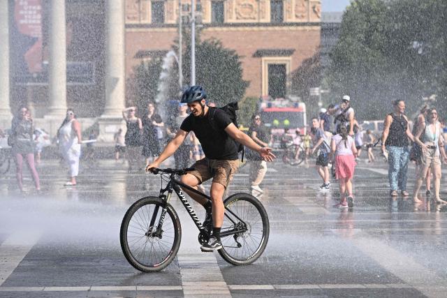 Police use water cannon to cool down people in Budapest's Heroes' Square during an extreme heat wave on June 30, 2026. Police and fire department vehicles sprayed water in the afternoon to relieve the high temperatures. The cooling initiative was well received by visitors, while a third-degree heat alert remains in effect nationwide and century-old heat (Photo by Attila KISBENEDEK / AFP)