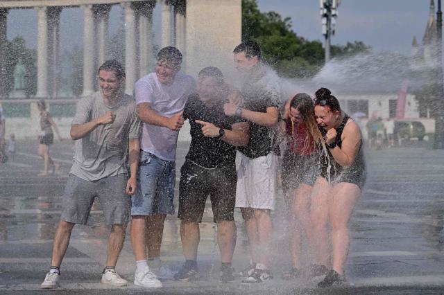 Police use water cannon to cool down people in Budapest's Heroes' Square during an extreme heat wave on June 30, 2026. Police and fire department vehicles sprayed water in the afternoon to relieve the high temperatures. The cooling initiative was well received by visitors, while a third-degree heat alert remains in effect nationwide and century-old heat (Photo by Attila KISBENEDEK / AFP)
