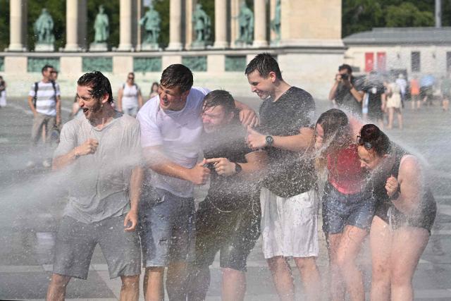 Police use water cannon to cool down people in Budapest's Heroes' Square during an extreme heat wave on June 30, 2026. Police and fire department vehicles sprayed water in the afternoon to relieve the high temperatures. The cooling initiative was well received by visitors, while a third-degree heat alert remains in effect nationwide and century-old heat (Photo by Attila KISBENEDEK / AFP)