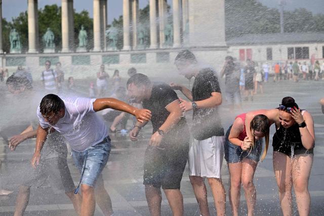 Police use water cannon to cool down people in Budapest's Heroes' Square during an extreme heat wave on June 30, 2026. Police and fire department vehicles sprayed water in the afternoon to relieve the high temperatures. The cooling initiative was well received by visitors, while a third-degree heat alert remains in effect nationwide and century-old heat (Photo by Attila KISBENEDEK / AFP)