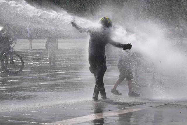 Police use water cannon to cool down people in Budapest's Heroes' Square during an extreme heat wave on June 30, 2026. Police and fire department vehicles sprayed water in the afternoon to relieve the high temperatures. The cooling initiative was well received by visitors, while a third-degree heat alert remains in effect nationwide and century-old heat (Photo by Attila KISBENEDEK / AFP)