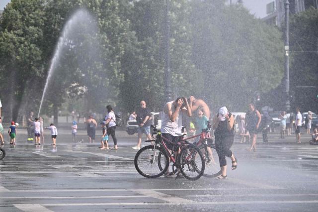 Police use water cannon to cool down people in Budapest's Heroes' Square during an extreme heat wave on June 30, 2026. Police and fire department vehicles sprayed water in the afternoon to relieve the high temperatures. The cooling initiative was well received by visitors, while a third-degree heat alert remains in effect nationwide and century-old heat (Photo by Attila KISBENEDEK / AFP)