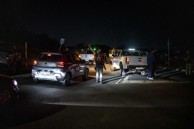 An officer of a Private Security Company gestures at a check point where in coordination with soldiers of the South African National Defence Forces (SANDF) patrol the scene of looting in the Umlazi area of Durban, on June 30, 2026. Thousands of demonstrators massed across South African cities on June 30, 2026, venting anger at undocumented foreign nationals as police mounted a major operation to head off looting and xenophobic violence that has claimed four lives.The nationwide protests cap weeks of demonstrations called by a loose coalition of minor political parties and small citizen-led vigilante groups, which set an unofficial June 30 deadline for foreigners without residency papers to leave. (Photo by MARCO LONGARI / AFP)