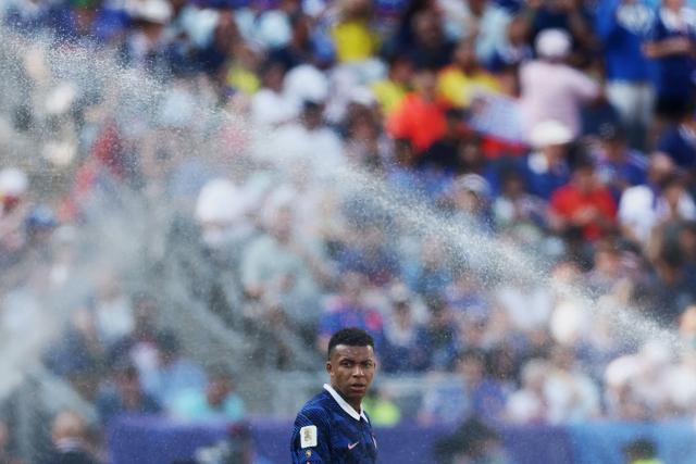 France's forward #10 Kylian Mbappe gestures as he is sprayed by the sprinklers during the 2026 World Cup round of 32 football match between France and Sweden at the New York/New Jersey Stadium in East Rutherford on June 30, 2026.  (Photo by CHARLY TRIBALLEAU / AFP)